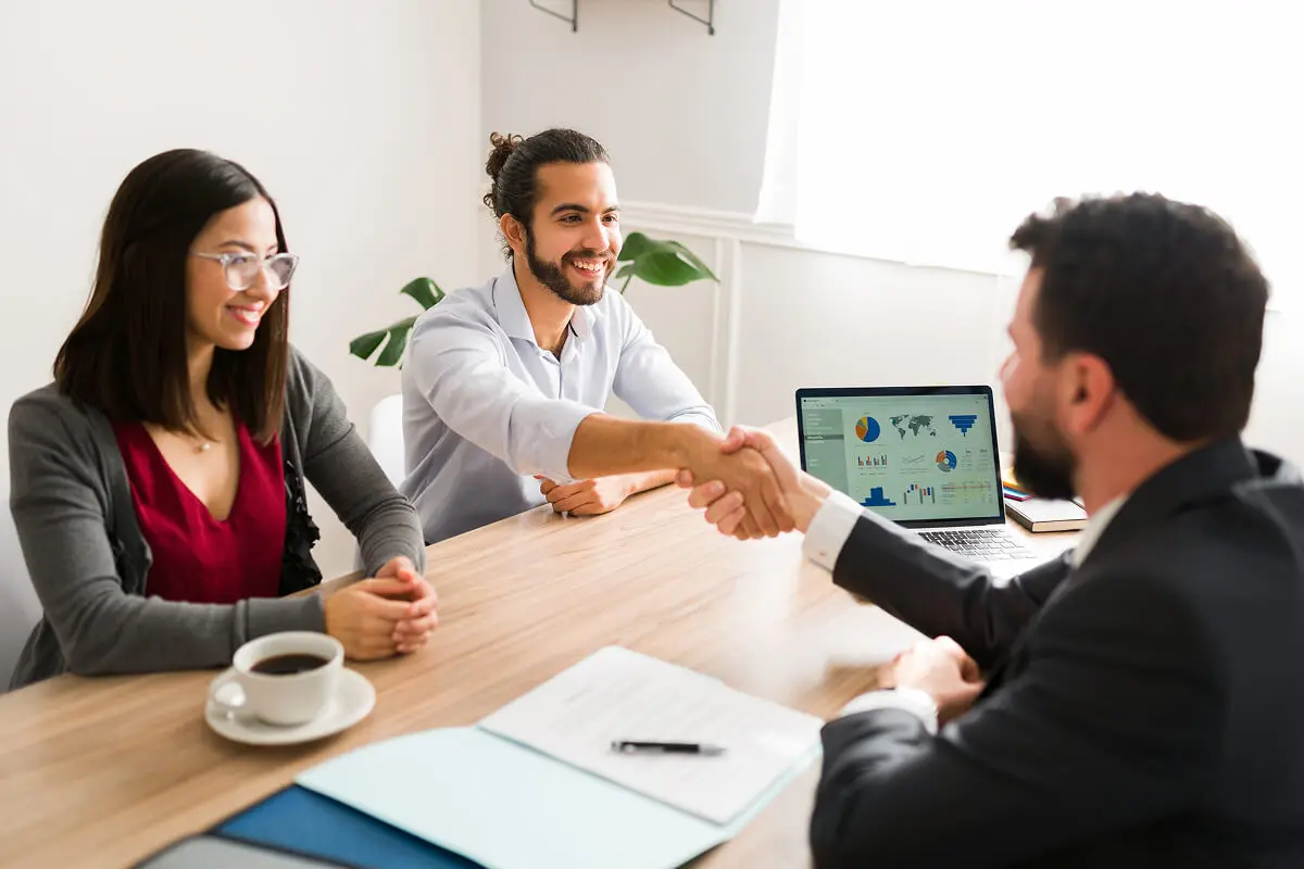 Three people in a business meeting handshake.